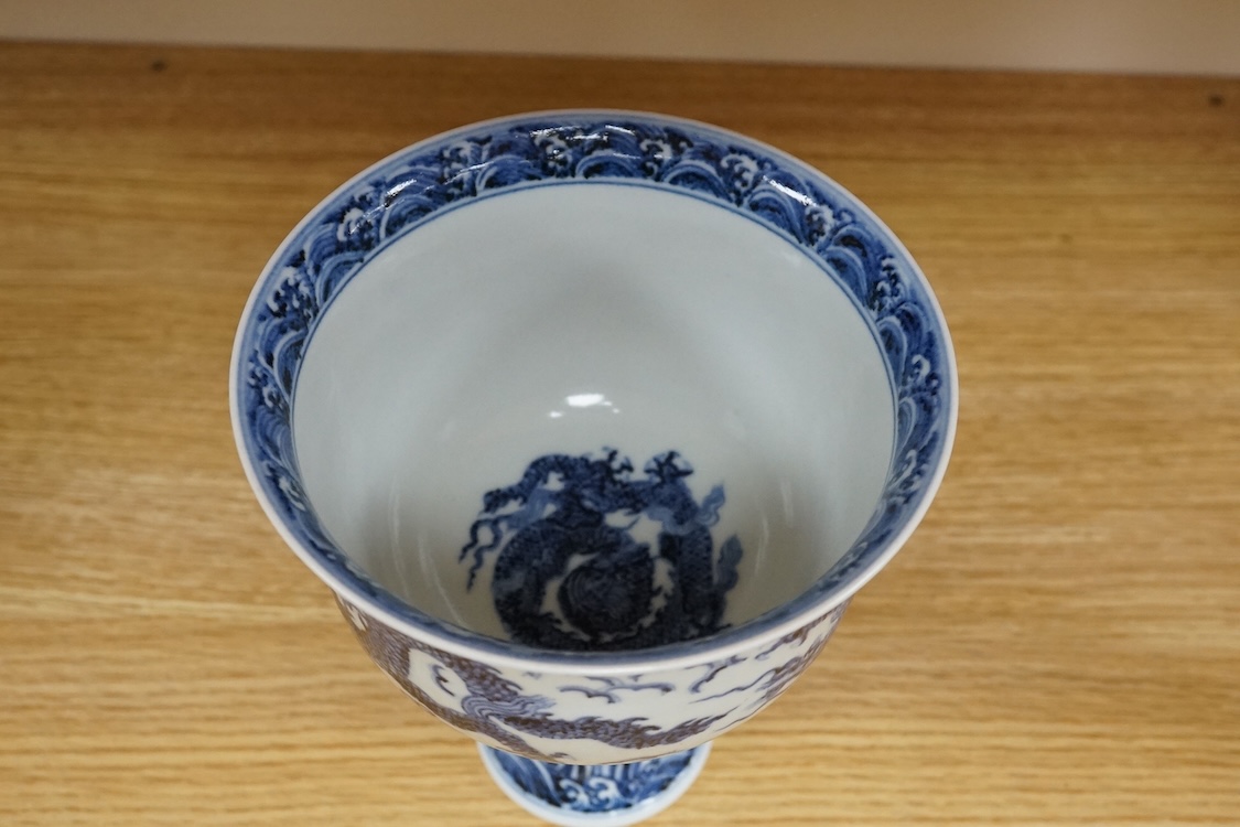 A Chinese blue and white stem bowl, painted with dragons in underglaze blue, 18cm high